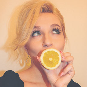 口元にオレンジを持っている目の大きな女性